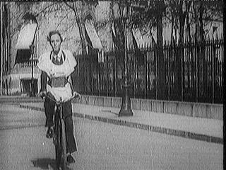 Biciklin fiatal frfi halad, klns ltzetben: gyerekruht visel az ltnye felett s egy doboz a nyakban
